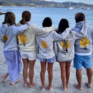 Grupo de personas en la playa con sudaderas