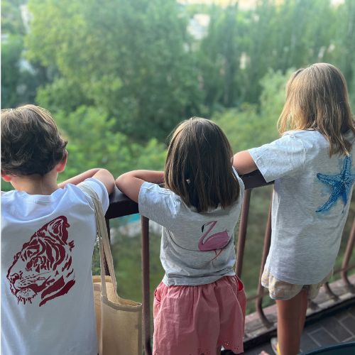 Niños mirando desde un balcón con camisetas